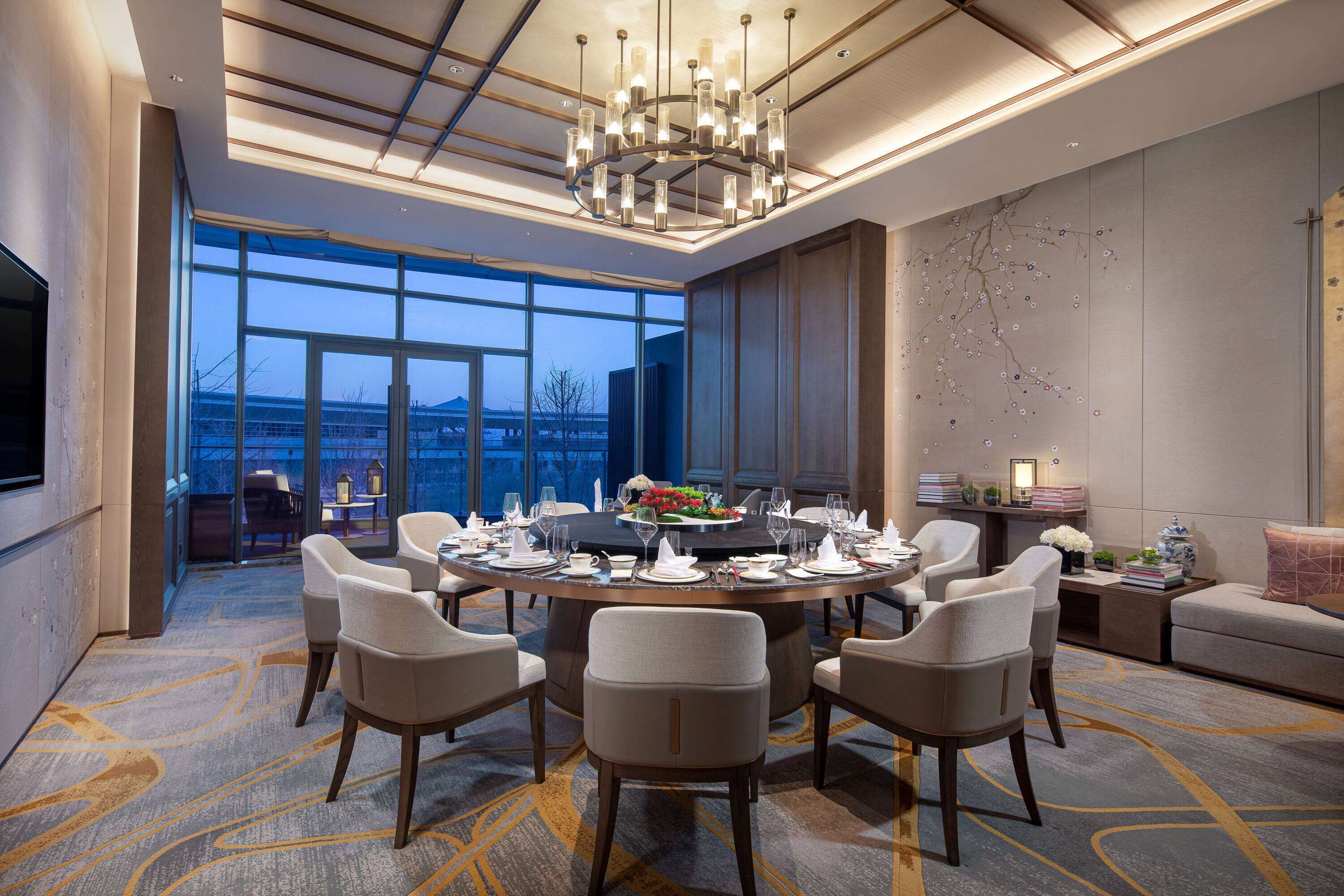 Un comedor moderno de hotel con una mesa redonda dispuesta para una comida, rodeada de sillas cómodas.