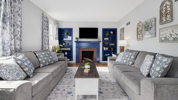 A living room with two grey sofas, a white coffee table, a blue fireplace, and a bookshelf. - Single-Level Kingsport Home · Sleeps 6 · Pets OK (Kingsport)