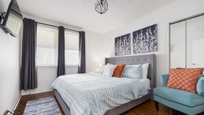 A bedroom with a bed, a chair, a TV, and artwork on the wall. - Single-Level Kingsport Home · Sleeps 6 · Pets OK (Kingsport)