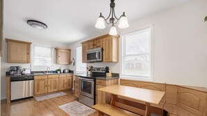 A kitchen with wooden cabinets, stainless steel appliances, a built-in oven, a microwave, and a bench at the island. - Single-Level Kingsport Home · Sleeps 6 · Pets OK (Kingsport)