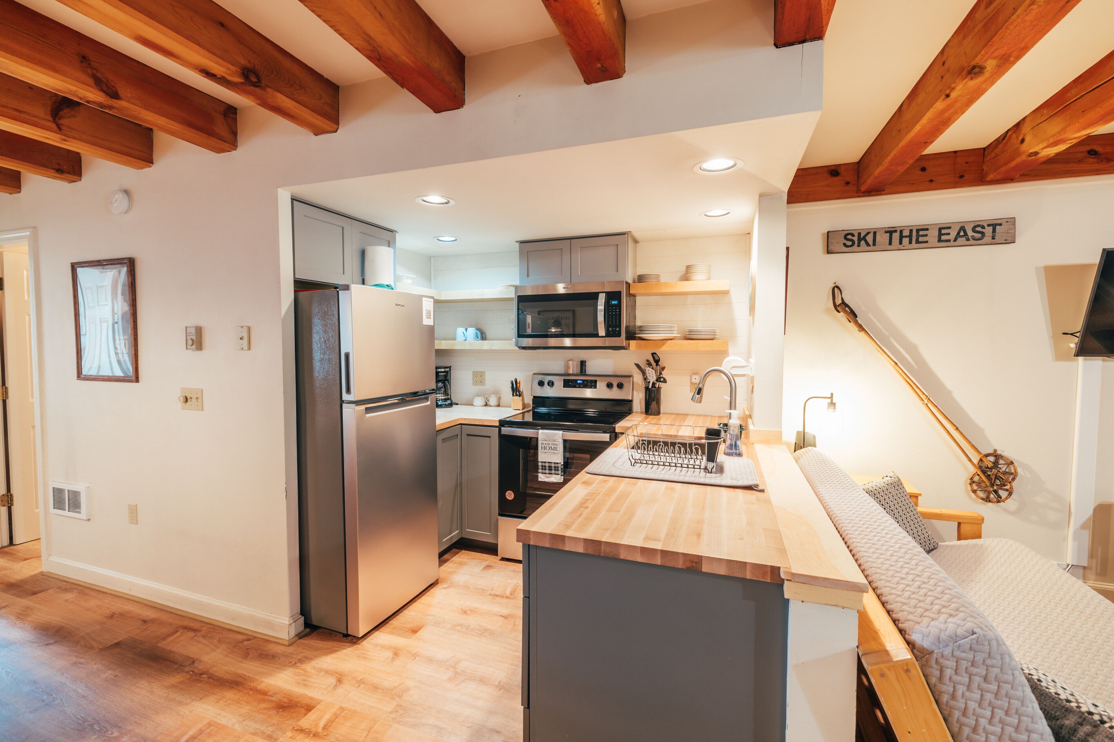 A modern kitchen with wooden beams, stainless steel appliances, and a sign that reads "SKI THE EAST".