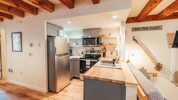 A modern kitchen with wooden beams, stainless steel appliances, and a sign that reads "SKI THE EAST".