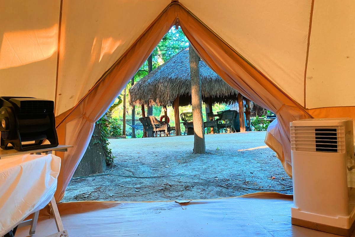 A tented accommodation with a table and an air conditioning unit inside.