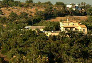 A large, two-story house with a tiled roof, surrounded by dense greenery and hills in the background. - Escape & Unwind in Elegance with Large Private Pool & Amazing Views (Free Wi-Fi) (Sao Bras de Alportel, Algarve)
