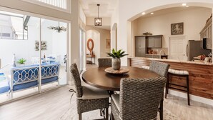 A modern kitchen with a wooden island, a dining area with wicker chairs, and a view of the backyard. - Ideal Location West of 41 - Minutes to the Beaches! (Naples)