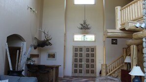 Un intérieur spacieux avec un plafond haut, une grande fenêtre en arc de cercle et un escalier en bois.