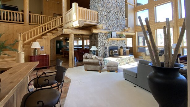 Un intérieur spacieux avec un plafond haut, des poutres en bois, un mur en pierre et une cheminée.