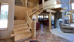 Un escalier en bois avec un mur en pierre, un coin repas avec des tables et des chaises, et un canapé.