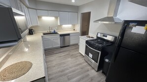 Una cocina moderna con armarios blancos, una estufa de acero inoxidable y un refrigerador negro.