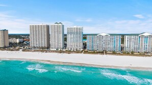 Un hotel frente a la playa con varios edificios altos, una playa de arena y aguas turquesas.