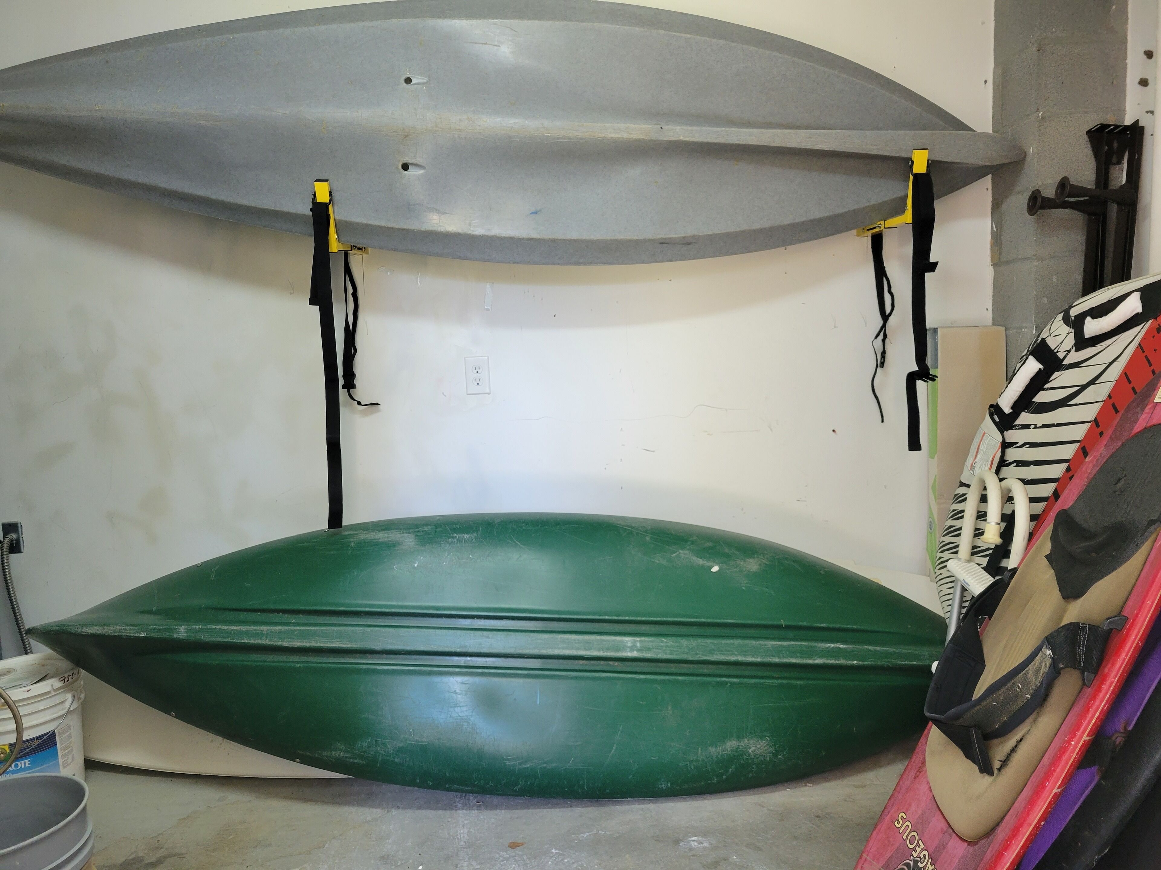 Two surfboards, one green and one grey, mounted on a wall with straps.