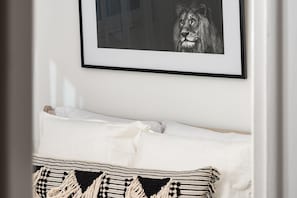 A neatly made bed with white bedding and a patterned throw pillow.