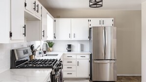 Eine moderne Küche mit weißen Schränken, einem Edelstahl-Kühlschrank und einem Gasherd.