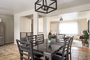 A dining area with a marble table, black chairs, and a pendant light.
