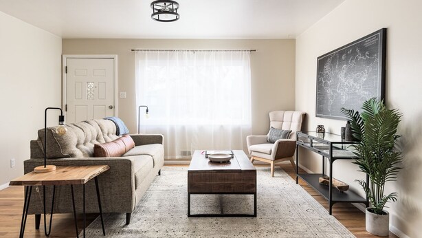 Ein modernes Wohnzimmer mit Sofa, Sessel, Couchtisch und einer Weltkarte an der Wand.