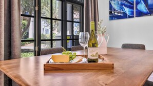 A wooden table with a tray containing a bottle of wine, glasses, cheese, and grapes. - Fabulous King 2BR/2BA/2Car Legacy Villa near Pool (La Quinta)