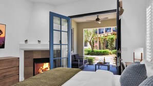 A bedroom with a fireplace, a bed, a view of the outside, and a dining area with a table and chairs. - Fabulous King 2BR/2BA/2Car Legacy Villa near Pool (La Quinta)