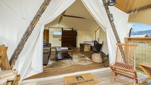 A tent with a wooden interior, including a table, chairs, and a sofa. - Under Canvas North Yellowstone  (Livingston)