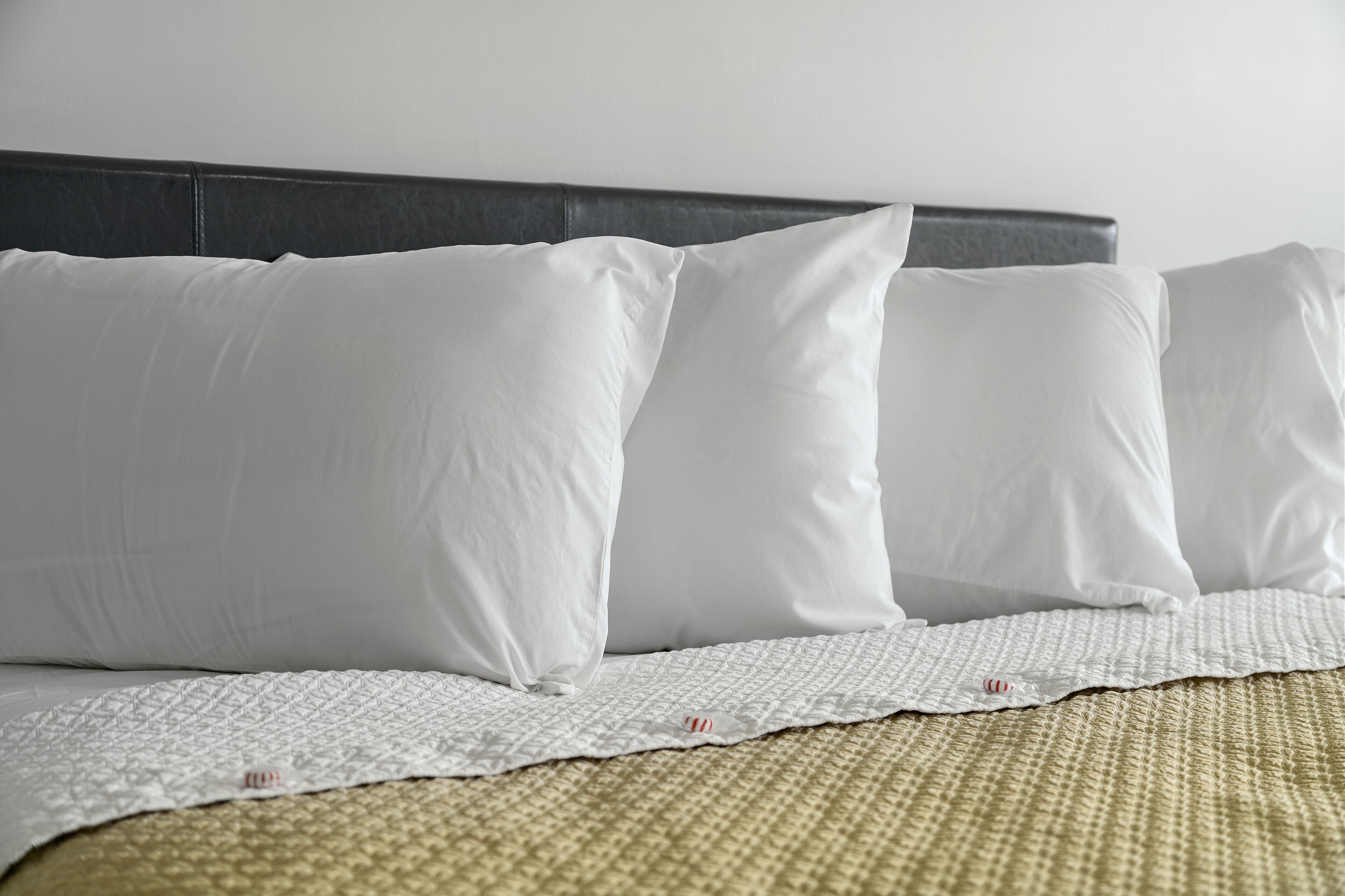 A neatly made bed with white pillows and a textured white bedspread.
