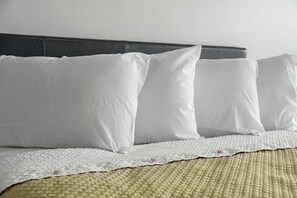 A neatly made bed with white pillows and a textured white bedspread. - The Mint Motel (Rock Springs)