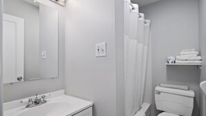 Ein Badezimmer mit weißem Waschbecken, Spiegel, Toilette und Duschvorhang.