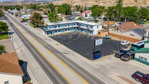 Ein Motel mit Parkplatz, ein Gebäude mit blau-weißer Fassade und einer Bergkulisse im Hintergrund.