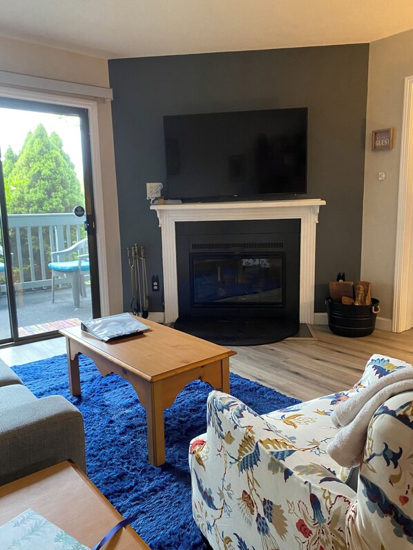 A living room with a fireplace, a television mounted above it, a sofa, and a coffee table.