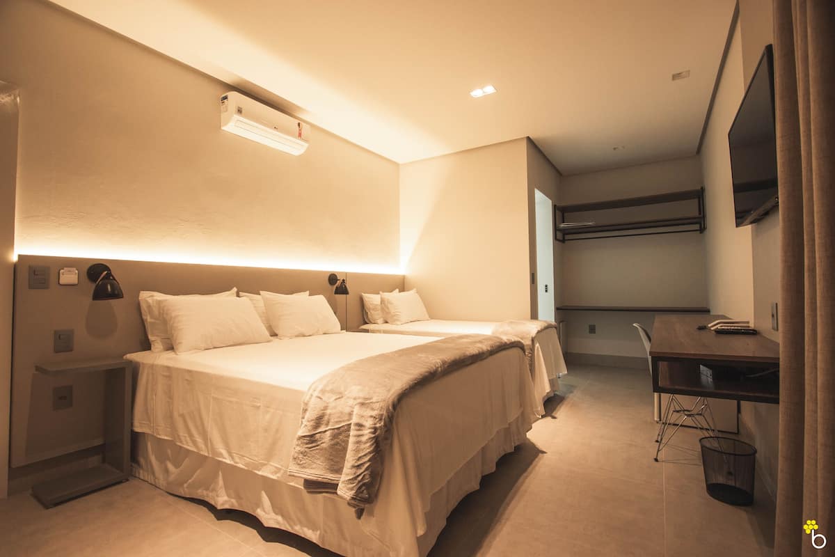 A hotel room with a large bed, bedside tables, a desk, and a TV mounted on the wall.