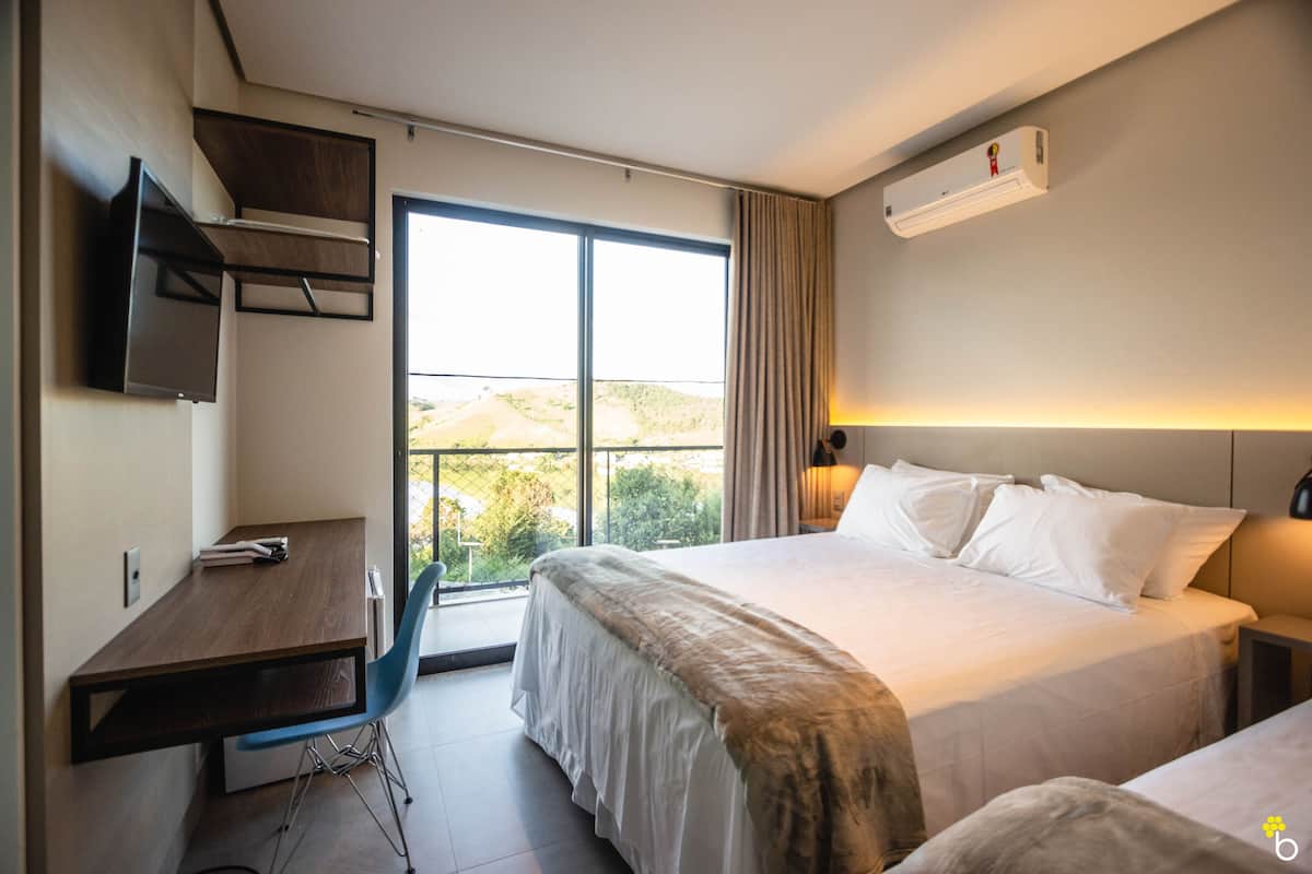 A hotel room with a bed, a desk, and a large window.