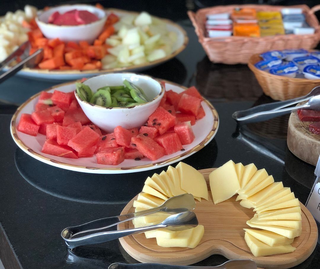 A buffet table with various food items including watermelon, kiwi, cheese, and other snacks.
