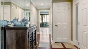 Un couloir avec une armoire en bois, un saladier en verre et une porte blanche.