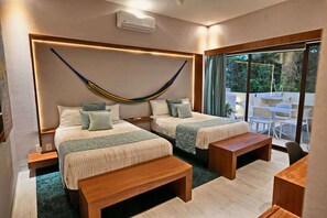 A modern hotel room with two beds, a hammock, and a balcony with outdoor seating.