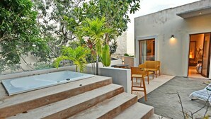 Eine moderne Außenpatio mit Whirlpool, Holzstufen und Gartenmöbeln.