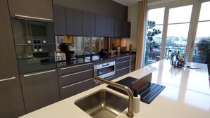Una cucina moderna con mobili scuri, elettrodomestici in acciaio inossidabile e un'ampia finestra che offre vista sulla città.