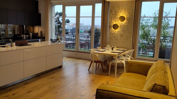 Una cucina moderna con zona pranzo, ampie finestre e un divano.