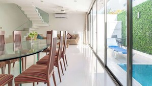 A modern interior with a glass dining table, striped chairs, a staircase, and a view of a swimming pool. - Wow! Gated House/WiFi/5 rooms/12 pax/Pool Private (Cancún)