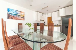 A modern kitchen with white cabinets, a stainless steel refrigerator, and a glass dining table with striped chairs. - Wow! Gated House/WiFi/5 rooms/12 pax/Pool Private (Cancún)
