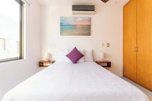 A bedroom with a bed, a nightstand, a wooden wardrobe, a painting, and an air conditioning unit. - Wow! Gated House/WiFi/5 rooms/12 pax/Pool Private (Cancún)