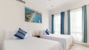 A hotel room with two beds, a painting of a coastal scene, and a large window with curtains. - Wow! Gated House/WiFi/5 rooms/12 pax/Pool Private (Cancún)
