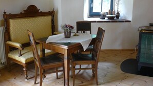 Un coin repas avec une table en bois, des chaises et un banc. Une fenêtre offre une vue sur la verdure à l’extérieur.