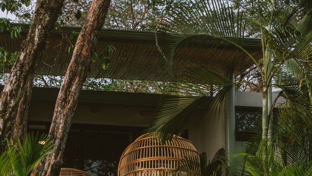 A stone staircase leading to a covered area with wicker furniture. - La Musa de la Jungla (Nosara)