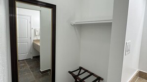 A bathroom with a large mirror, a towel rack, and a countertop.