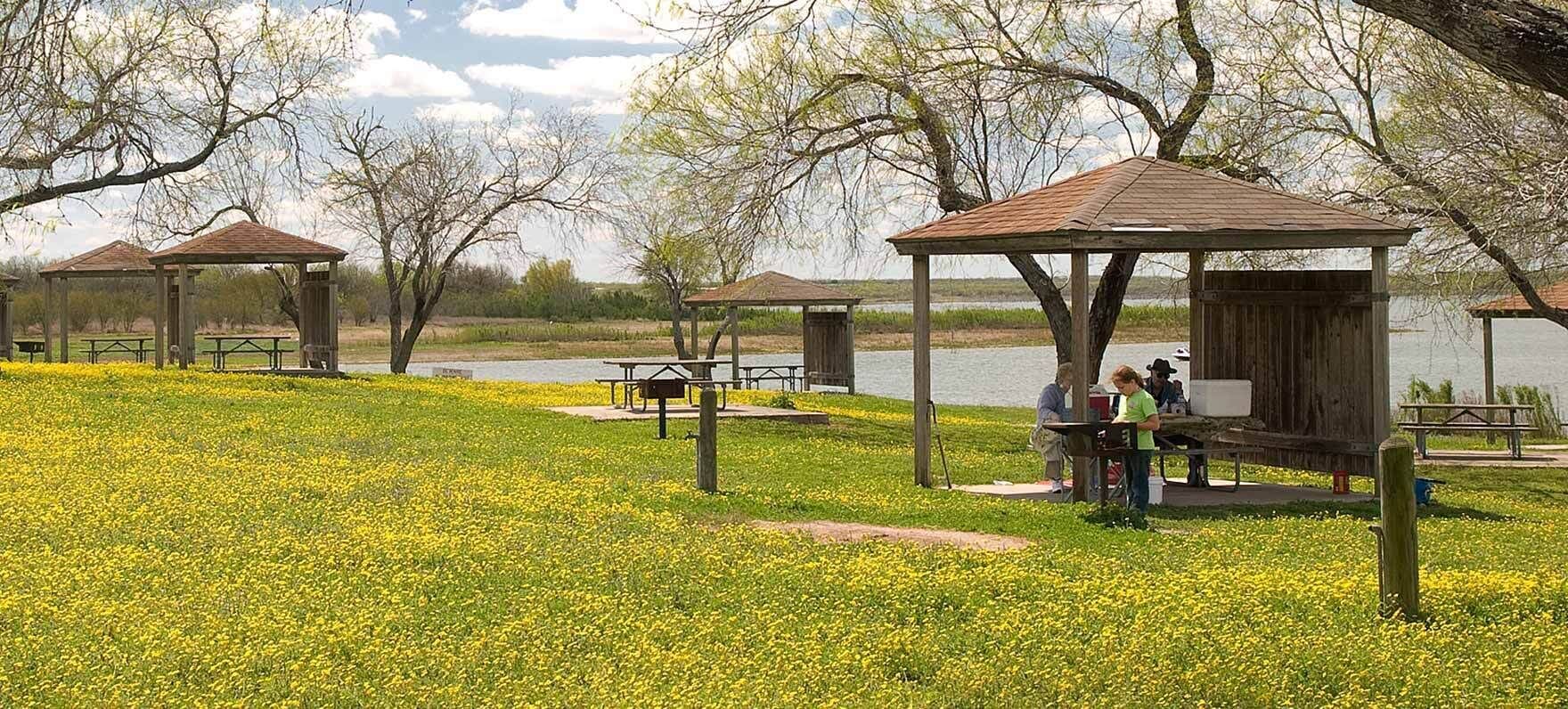 A park with picnic areas, benches, and a lake.