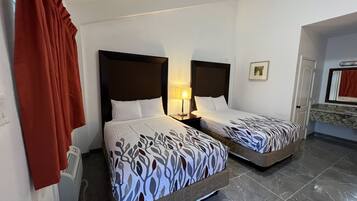 Een hotelkamer met twee bedden, een nachtkastje met een lamp, een badkamer met een spiegel en een rood gordijn.