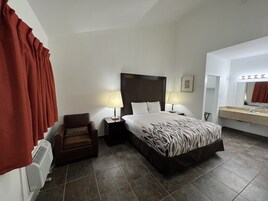 Habitación de hotel con cama, dos lámparas de noche, una silla, cómoda, espejo y radiador.