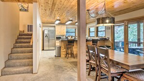 Un intérieur en bois avec un escalier, une cuisine, un coin repas et de grandes fenêtres.