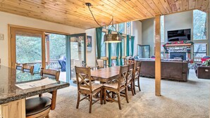 Un plafond en bois, une table à manger avec des chaises, une cheminée et un téléviseur.