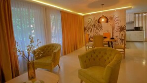 Una sala moderna con dos sillones amarillos, una mesa redonda de centro y una zona de comedor con mesa y sillas.