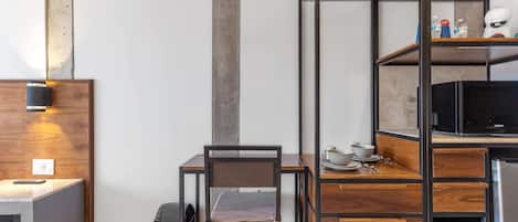 A compact kitchen with a wooden table, a chair, and a built-in microwave.
