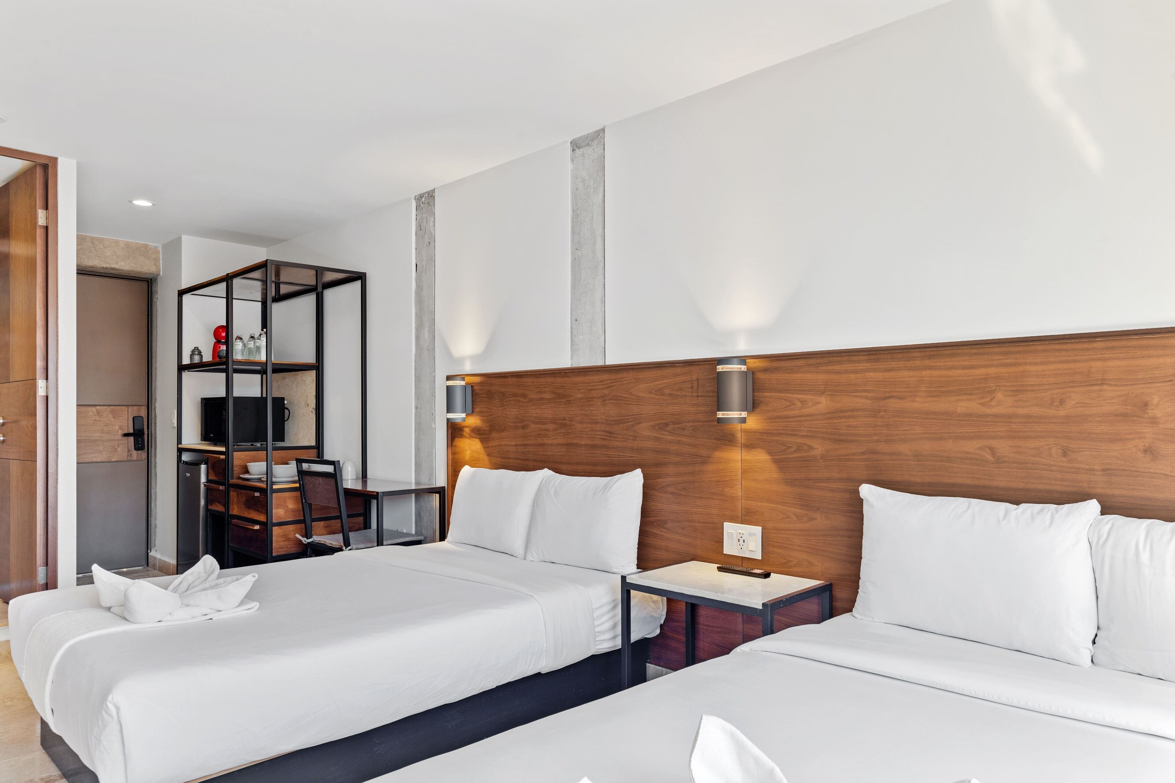 A hotel room with two beds, a desk, a chair, and a small seating area with a table and chairs.